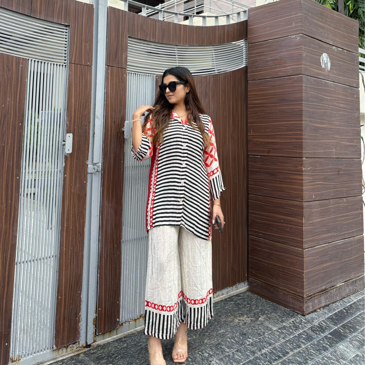 Black and White Striped Top With Orange Patterns And White Pants With Orange Geometrical Patterns